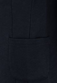 Primo piano di una tasca di tessuto blu scuro cucita su materiale abbinato, con cuciture verticali visibili e dettagli di cucitura sopra.