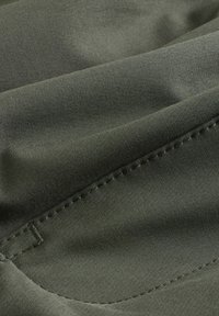 Tume roheline riie, mis näitab siledat tekstuuri ja õmbluste detaile, sisaldab pehmeid voldikuid ja kaari, viidates kergele rõivale.