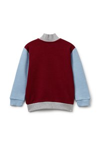 Jersey rojo y azul claro con cuello y puños grises; presenta una textura suave y mangas en contraste.