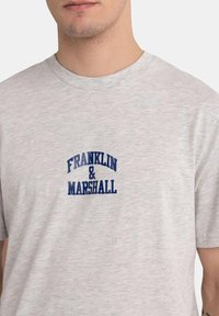 Helles graues Baumwoll-T-Shirt mit einem navyblauen Drucklogo "FRANKLIN & MARSHALL" auf der Brust, klassischem Rundhalsausschnitt und kurzen Ärmeln.