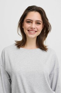 Lichtgrijze oversized sweater van zachte, gladde stof. Heeft een brede halslijn en verlaagde schouders voor een ontspannen pasvorm. Geen patronen of accenten.