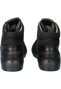 Par av svarta högskor som visas från baksidan, med läder- och mockamaterial och tjocka sulor.