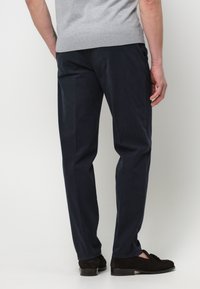 Pantaloni navy in una vestibilità rilassata, realizzati in cotone con una texture liscia. Tasche sui lati, con una piega sottile sul davanti.