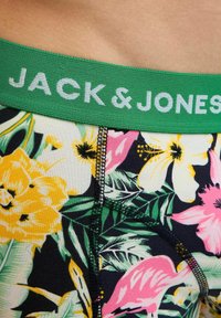 Grüner Bund mit der Aufschrift "JACK & JONES" auf Unterwäsche mit floralem Muster, die gelbe, pinke und weiße Blumen mit grünen Blättern zeigt.