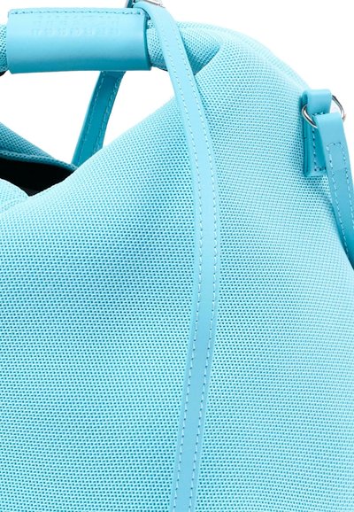 Sac à main en tissu bleu clair texturé avec des anses assorties et des détails en anneaux métalliques argentés, présenté en gros plan.