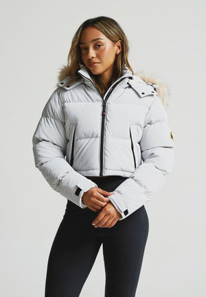 Valkoinen padded cropped takki vaaleanharmaana, jossa on tekoturkishuppu, musta vetoketju, sivutaskut ja säädettävät hihansuut. Sileä tekstuuri, lämminsuojaus.