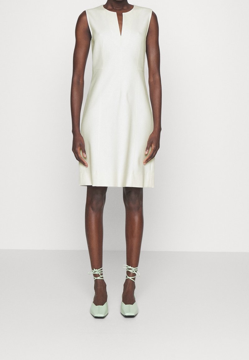 Robe sans manches vert menthe avec un décolleté en V, une texture lisse et une coupe ajustée, associée à des ballerines à nouer à la cheville de couleur vert menthe clair.