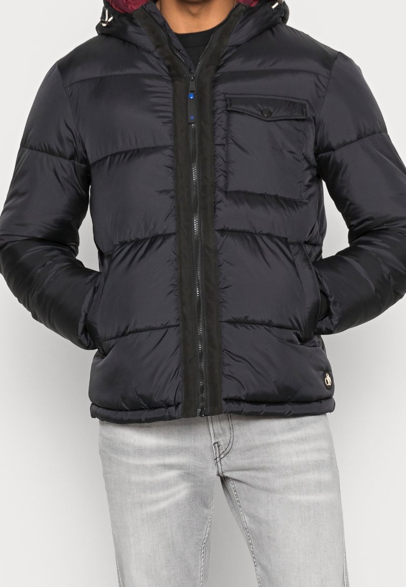 Pánská černá prošívaná bunda s kapucí, s prošitou texturou, předním zipem, kapsou na hrudi a černým lemováním podél zipu.