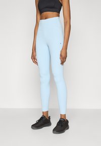 hele sinised retuusid, valmistatud venivast materjalist, kõrge vöökohaga ja väike logo detail küljel. Kombineeritud mustade spordijalatsitega.