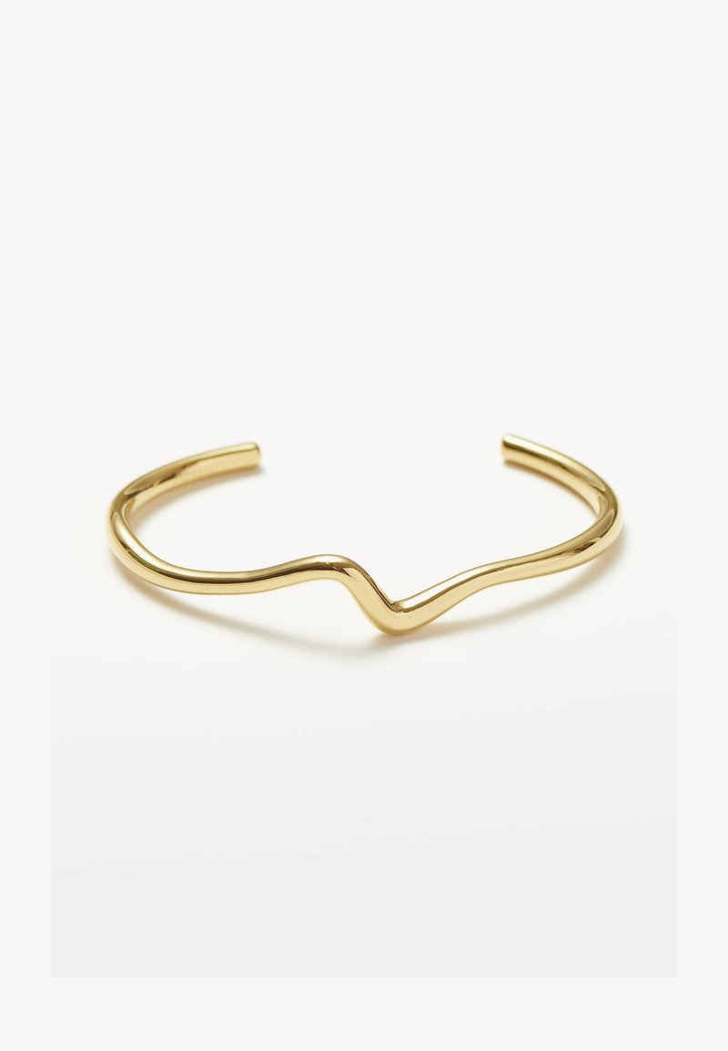 Kuldne käevõru lainelise kujundusega. Sile, poleeritud metall, millel on minimalistlik kuju ja ümarad otsad. Lisakaunistusi pole.