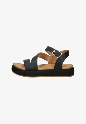 Zwarte leren sandalen met kruislings bandjes, verstelbare gespsluiting en een dikke zwarte plateauzool. Het tan-kleurige voetbed voegt contrast toe.