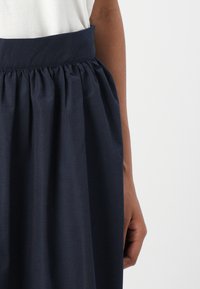 Marineblauer Rock mit breitem, gerafftem Bund und plissiertem Design. Hergestellt aus leichtem Stoff, hat er eine glatte Textur und klare Linien.