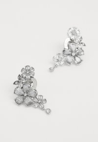Orecchini floreali argento con forme di petali multipli, caratterizzati da pietre chiare brillanti e un accento a goccia. Design e texture intricati.