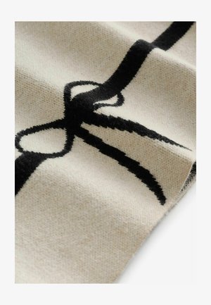 Tekstil med en cremefarvet baggrund, der har et fremtrædende sort sløjfedesign. Blød tekstur, vævet stof med synlige fibre og mønstre.