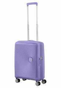Valigia rigida viola con motivo ondulato, manico retrattile in alluminio, quattro ruote nere e lucchetto a combinazione sul lato.