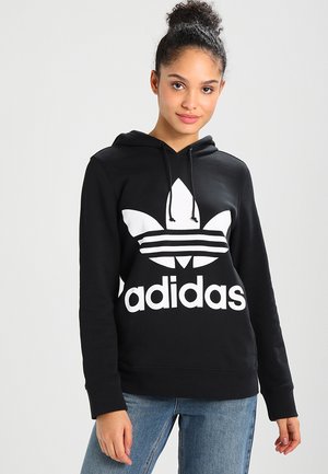 Felpa nera con cappuccio caratterizzata da un grande logo Adidas bianco e design a tre strisce. Realizzata in tessuto morbido con una vestibilità comoda e cappuccio regolabile.