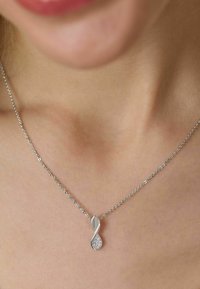 Srebrny naszyjnik z kręconym wisiorkiem o gładkim, wydłużonym kształcie i dekoracyjnymi, błyszczącymi akcentami z jednej strony.