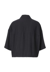 Chemise noire oversize à manches courtes avec col et ourlet élastique, vue de dos sur fond blanc.