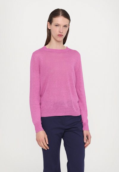 Maglione rosa a maglia con scollo rotondo, maniche lunghe e polsini e orlo a costine. Indossato sopra pantaloni blu navy, caratterizzati da una texture liscia.