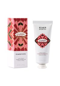 Handcreme in einer weißen Tube mit einer dekorativen rosa-roten geometrischen Verpackung mit goldenen Akzenten. Auf dem Produkt steht "Cedar Poinsettia".