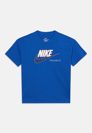 Μπλε κοντομάνικη μπλούζα Nike με μεγάλο λευκό και πορτοκαλί λογότυπο και το κείμενο «FRANCE» στην μπροστινή πλευρά, σε ανοιχτό γκρι φόντο.