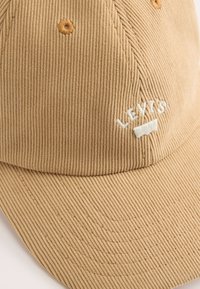 Tan corduroy cap with raised texture, featuring white embroidered "LEVI'S" logo and decorative stitching on the crown and visor.