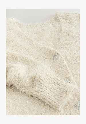 Heledbeige kardigan, mis on valmistatud kohevast, tekstuuriga lõngast. Omab sügavat kaelust ja metallnuppe ees. Pehme ja soe kangas.