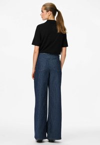 Platas kājas, svītraini bikses tumšā denima. Augstā vidukļa dizains ar gludu apdari, ietver divas aizmugurējās kabatas un kontrastējošas svītras.