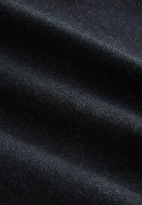 Sort stof med en blød tekstur, der viser subtile bølger og en let glans. Materialet ser ud til at være en blanding, der understreger varme og holdbarhed.