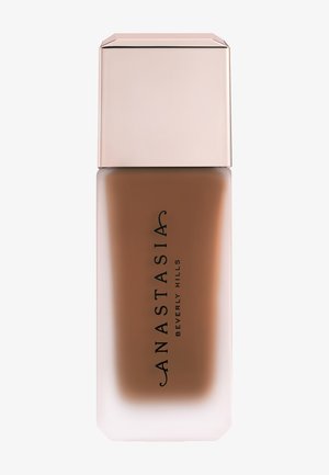 Flacon de fond de teint liquide mat avec verre satiné et bouchon beige clair, étiqueté "Anastasia Beverly Hills" en texte noir.