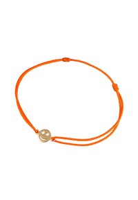 Bracelet en corde orange avec un charme en métal doré en forme de smiley. Le design comprend deux cordes ajustables nouées pour maintenir le charme.