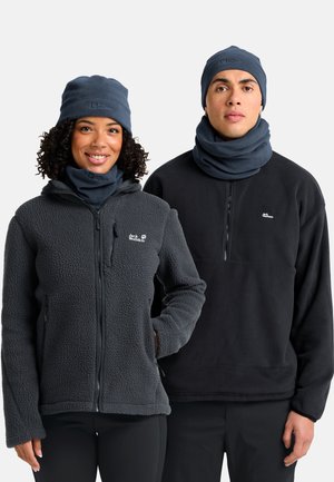 Due persone indossano giacche in pile di colore grigio scuro e nero; entrambe hanno cappelli a maglia e sciarpe per il collo in una tonalità scura simile.