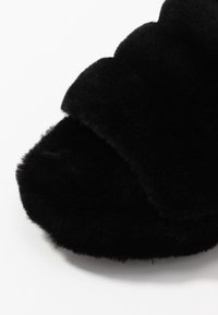Black fuzzy open-toe slide slippers with a soft, plush texture on a white background.