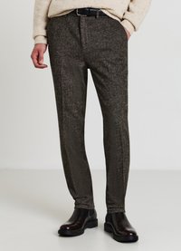 Texturierte, dunkelbraune, maßgeschneiderte Hose mit schmaler Passform, seitlichen Taschen und glattem Finish, kombiniert mit schwarzen Lederstiefeln.