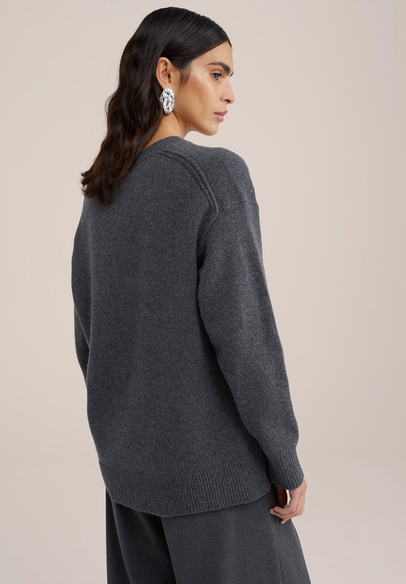 Grijze gebreide trui met een geribde zoom en mouwen. Heeft een ronde halslijn en een ontspannen pasvorm. Zacht textuur, minimalistisch ontwerp.
