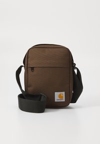 Geantă de umăr din material maro, cu formă rectangulară, închidere cu fermoar și curea neagră ajustabilă. Prezintă o etichetă logo galbenă pe partea din față.