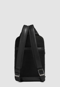 Zaino nero con tessuto a trama e dettagli in pelle. Presenta spallacci regolabili e un compartimento con zip nella parte superiore.