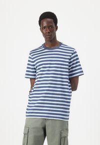 Stribet T-shirt i marineblå og lys blå, lavet af bomuldsstof, med rund hals, korte ærmer, med jævne vandrette striber i varierende bredder.