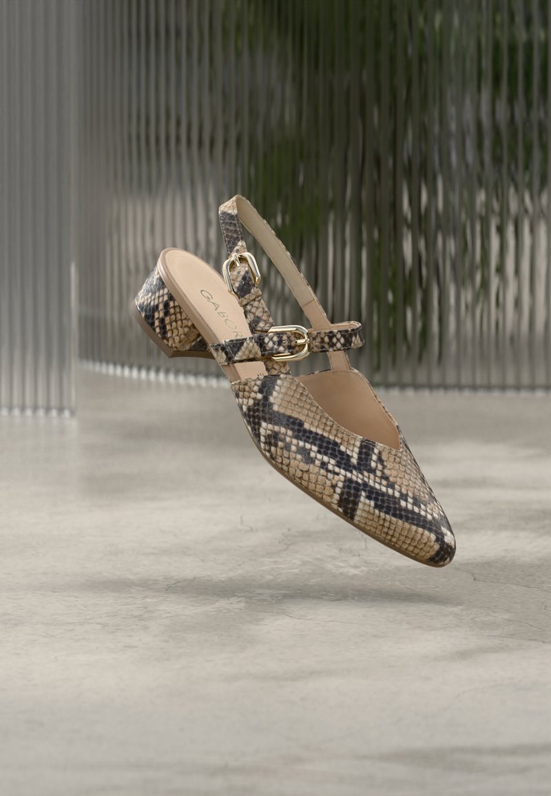 Women's low-heeled slingback shoe with snakeskin pattern, two gold buckles, shown mid-air above a light concrete floor.