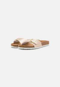 Flate sandaler med en teksturert lyserosa stropp, med en gullspenne som detalj. Korkfotbed med en hvit gummisåle.