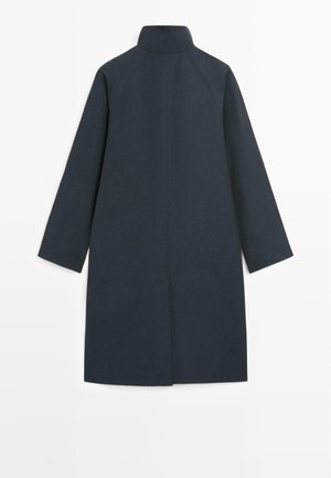 Długi ciemnogranatowy płaszcz z wysokim kołnierzem i długimi rękawami, prosty krój i detal rozcięcia z tyłu.