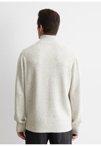 Hellgrauer, strukturierter Pullover mit hohem, geripptem Kragen, gerippten Ärmelbündchen und Saum, der ein gesprenkeltes Muster aufweist.