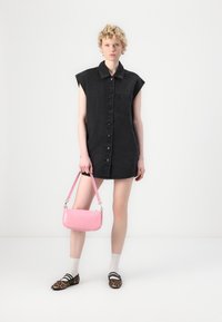 Zwarte denim jurk met kraag, knopen aan de voorkant en zak; gecombineerd met een roze handtas en kleurige flats met een luipaardprint, gedragen met gestreepte sokken.