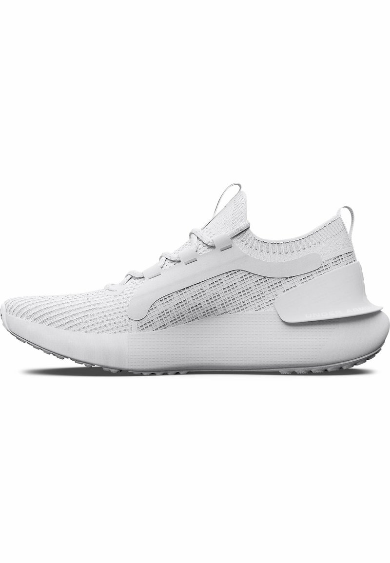 Zapatilla deportiva blanca con un upper texturizado, detalles de malla y una suela gruesa. Presenta cordones y una lengüeta en la parte posterior para facilitar su uso.