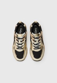 Black and gold athletic shoes feature mesh and synthetic materials, a chunky design, white accents, and black laces. Optimized for comfort.