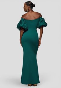 Turkusowa sukienka z opuszczanymi ramionami, z falbanami na rękawach, dopasowanym krojem i zamkiem błyskawicznym z tyłu. Gładka faktura, długość do podłogi.