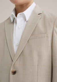 Beige karierter Blazer aus strukturiertem Stoff, mit einreihiger Knopfverschluss und Reverskragen, kombiniert mit einem knackigen weißen Hemd.