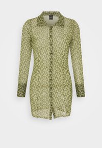 Camisa transparente de manga longa em verde-oliva com um padrão geométrico, frente com botões e um colarinho com um destaque em verde mais escuro.