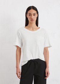 White short-sleeve t-shirt with a crew neck and chest pocket, made of soft fabric. Paired with black drawstring pants.