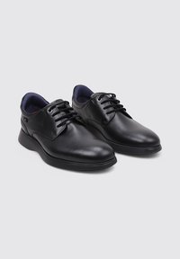 Zapatos de cuero negro con un acabado liso, punta redondeada y cordones. Presentan una suela acolchada y un forro interior azul contrastante.